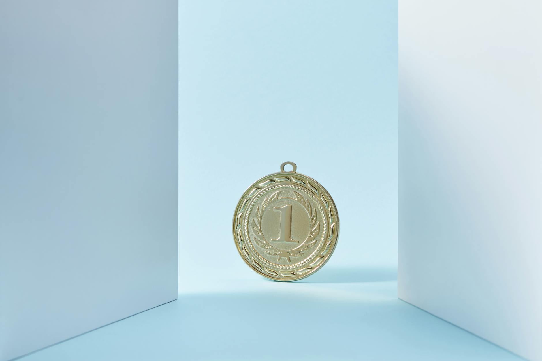 A gold medal displaying the number one, set against a light blue background.